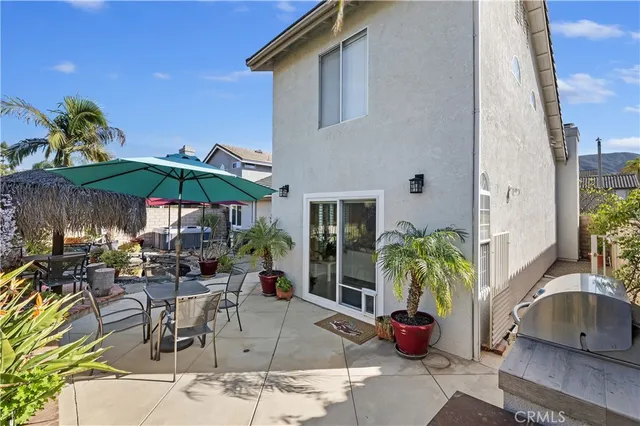 a patio with a table and chairs under an umbrella with potted plants
