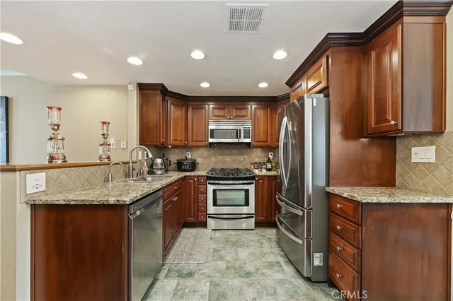 a kitchen with stainless steel appliances granite countertop a sink stove refrigerator and cabinets