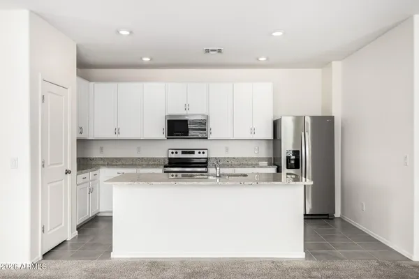 a kitchen with stainless steel appliances granite countertop a stove a refrigerator a sink and white cabinets