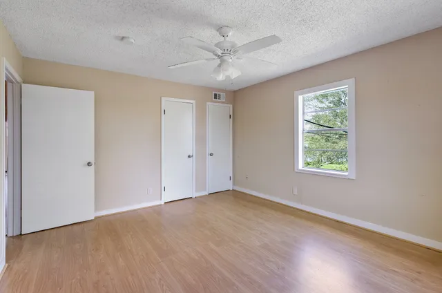 an empty room with a window and a fan