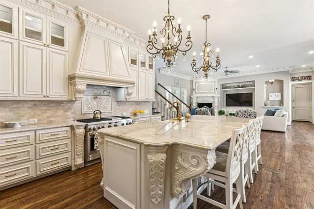 a kitchen with stainless steel appliances kitchen island granite countertop a stove top oven a sink a dining table and chairs with wooden floor