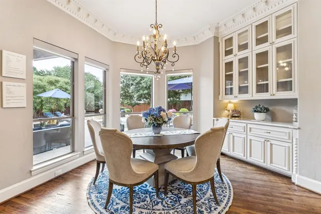 a dining room with wooden floor a chandelier a wooden table and chairs