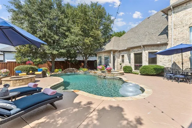 a view of a patio with couches table and chairs under an umbrella