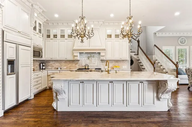 a kitchen with stainless steel appliances kitchen island granite countertop a refrigerator a stove a oven and white cabinets with wooden floor