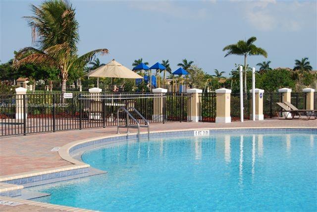 22801 Southwest 88th Place, Unit 205 Cutler Bay, FL 33190 - Photo 25 of 36 a view of a swimming pool with a table and chairs