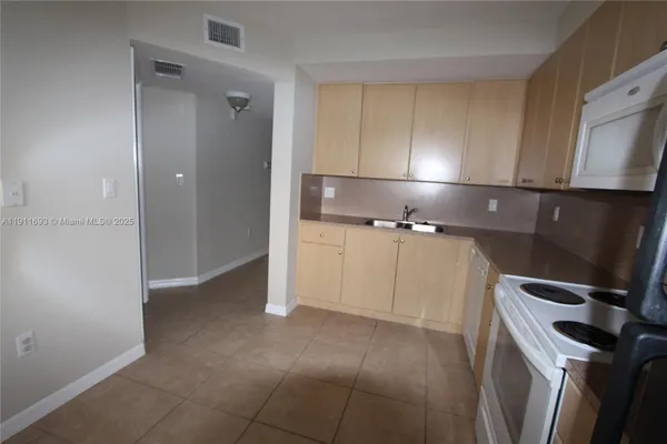 a kitchen with a refrigerator sink and cabinets