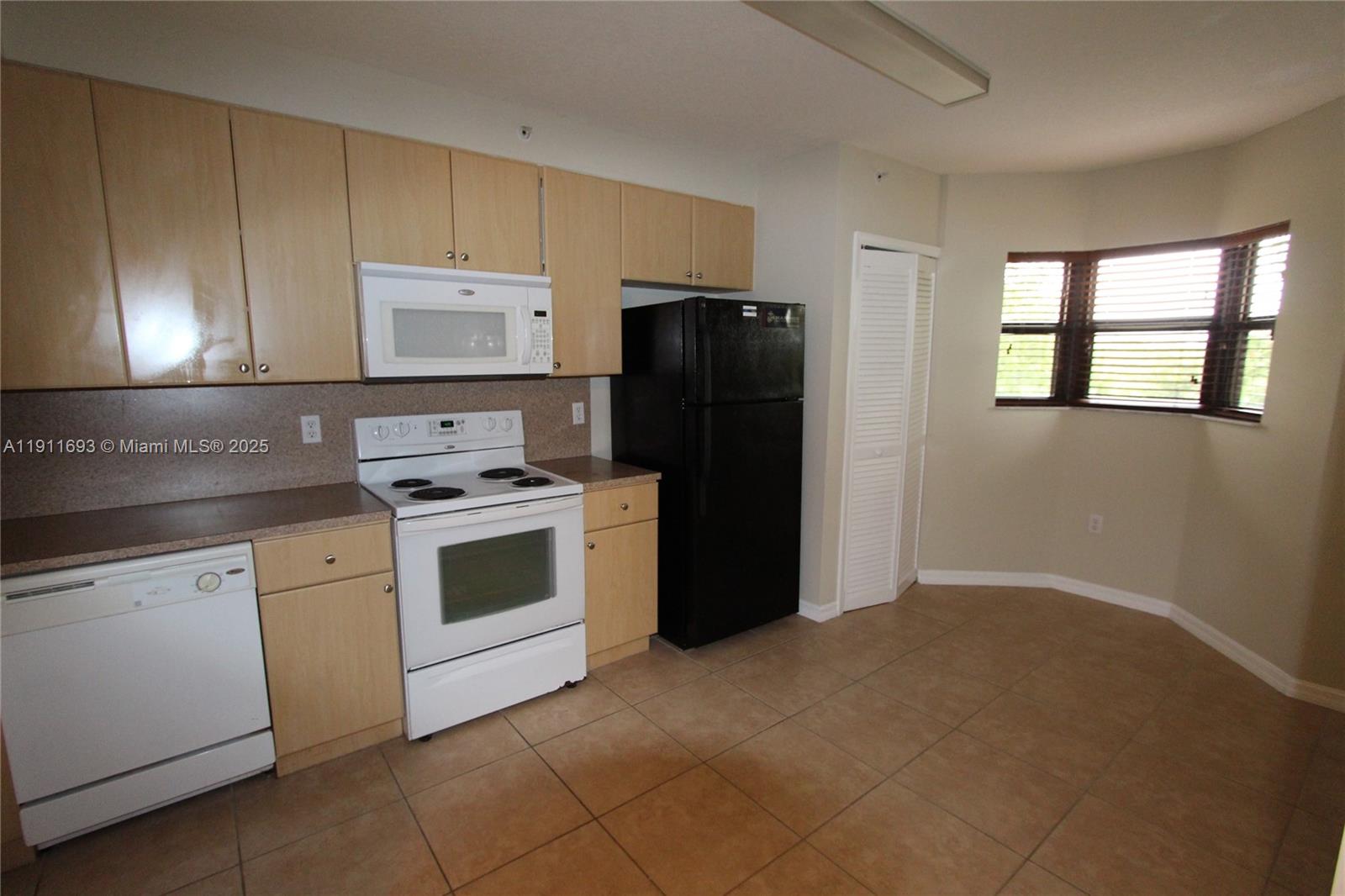 22801 Southwest 88th Place, Unit 205 Cutler Bay, FL 33190 - Photo 7 of 36 a kitchen with a stove a sink and a refrigerator
