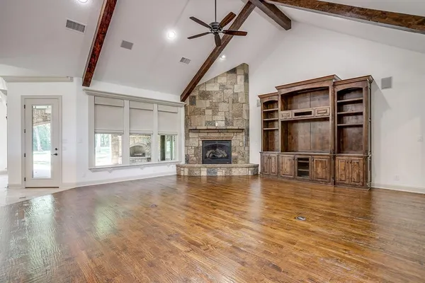 a view of an empty room with wooden floor fireplace and a window