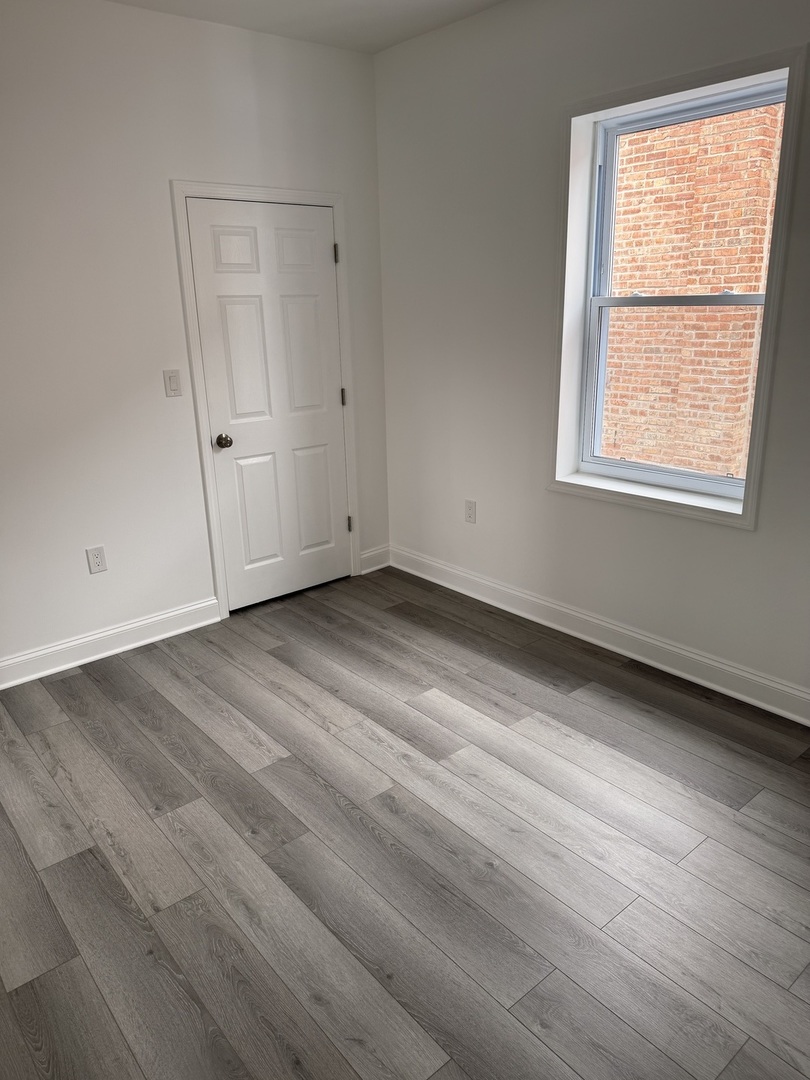 2101 Gunderson Avenue, Unit 2 Berwyn, IL 60402 - Photo 9 of 11 an empty room with wooden floor and windows