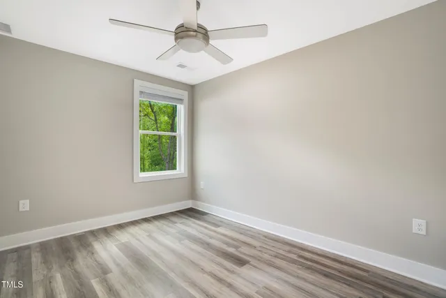 an empty room with a window and a ceiling fan