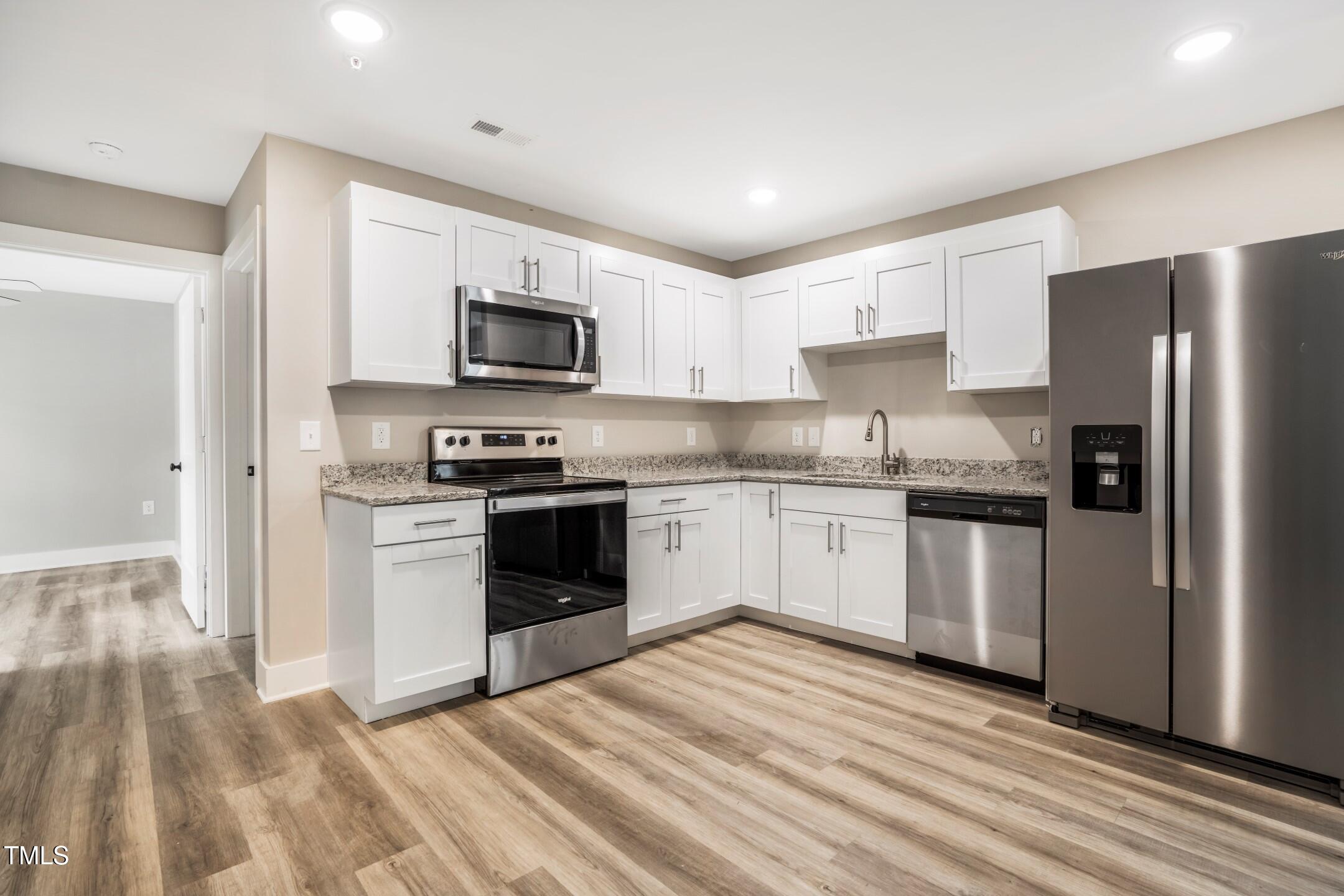 303 Linwood Street, Unit 306 Apex, NC 27502 - Photo 2 of 19 a kitchen with granite countertop a refrigerator stove and microwave