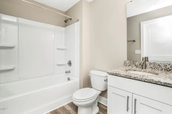 a bathroom with a granite countertop toilet a sink and a bathtub