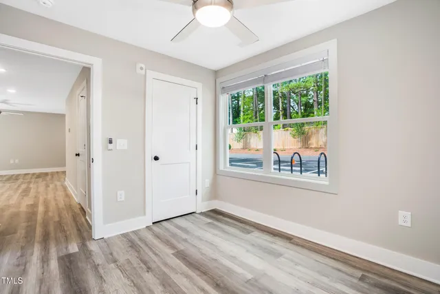 a view of an empty room with wooden floor and a window