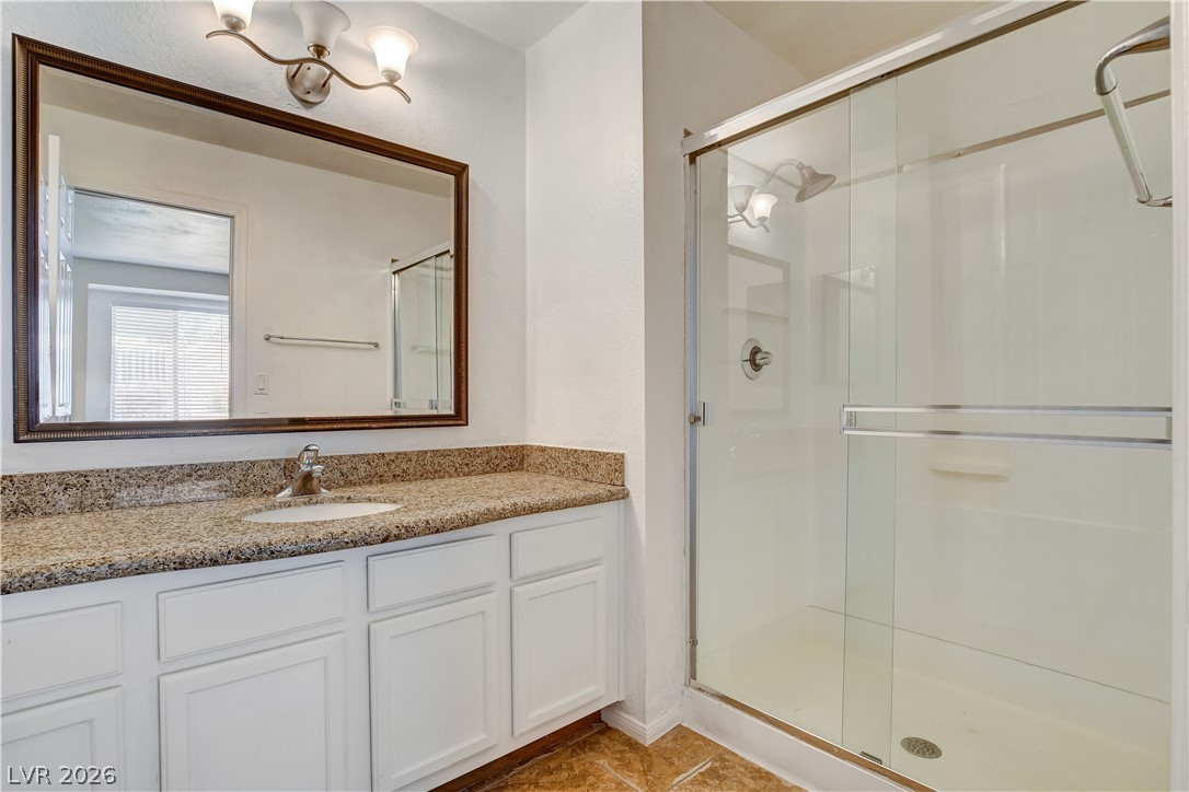 7200 West Pirates Cove Road, Unit 1050 Las Vegas, NV 89145 - Photo 13 of 24 Bathroom featuring a shower stall, vanity, and light tile patterned floors