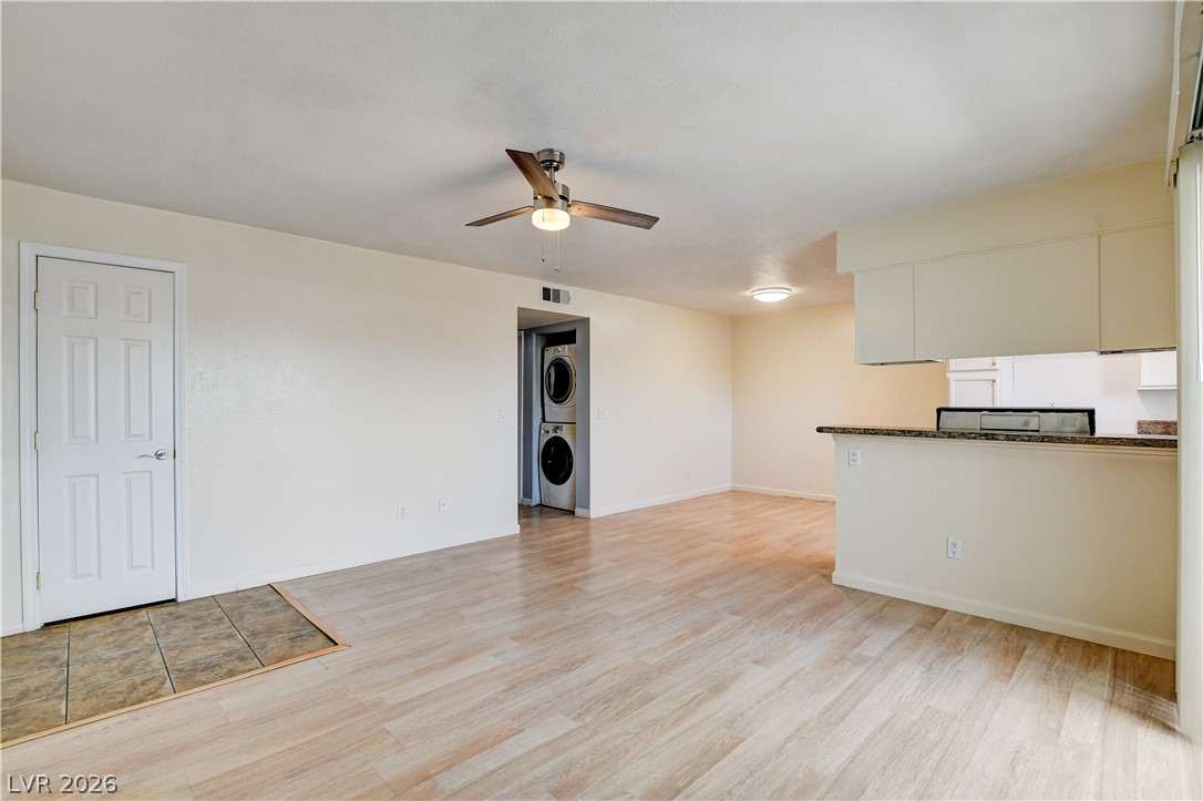 7200 West Pirates Cove Road, Unit 1050 Las Vegas, NV 89145 - Photo 5 of 24 Unfurnished living room featuring a ceiling fan, light wood-type flooring, and stacked washing machine and dryer