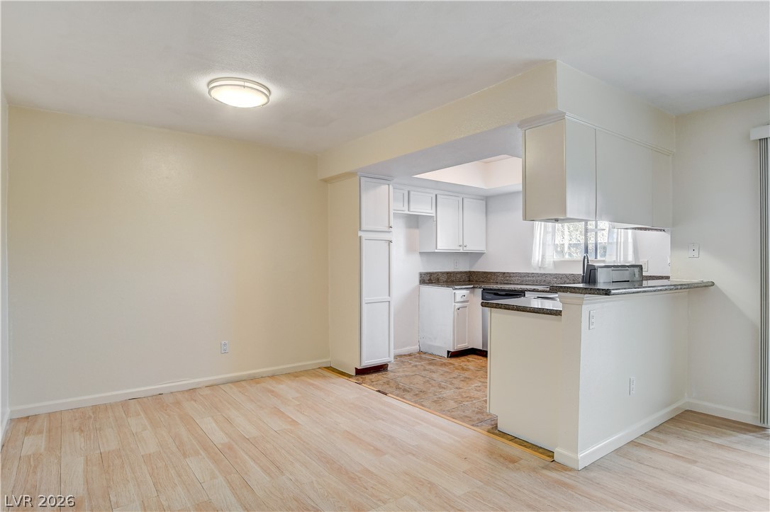 7200 West Pirates Cove Road, Unit 1050 Las Vegas, NV 89145 - Photo 9 of 24 Kitchen featuring light wood-type flooring, white cabinets, and a peninsula