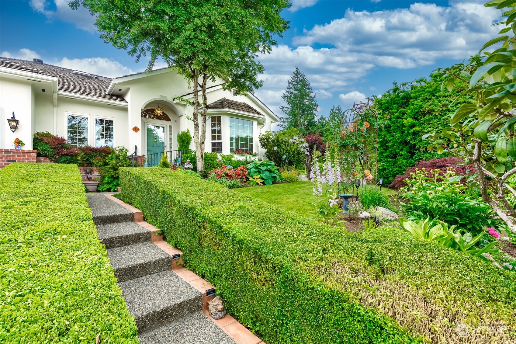 a view of a white house with a yard and potted plants
