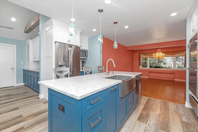 a kitchen with a sink a counter top space stainless steel appliances a large window and wooden floor