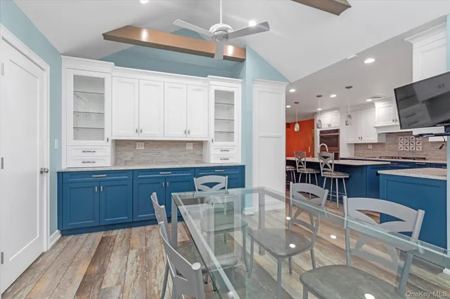 a kitchen with stainless steel appliances kitchen island granite countertop a stove a sink a dining table and chairs with wooden floor