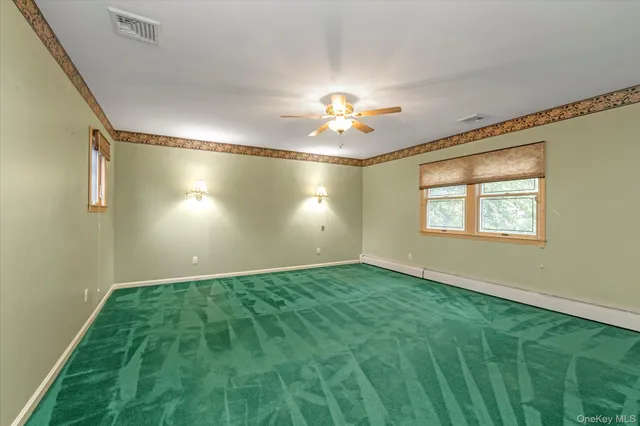 a view of an empty room with window and chandelier fan