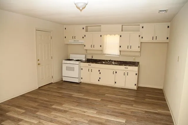 a kitchen with granite countertop white cabinets and white appliances