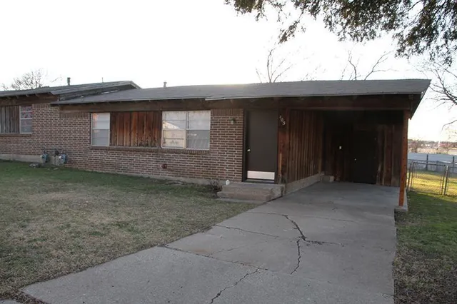 a view of a house with a small yard and large tree