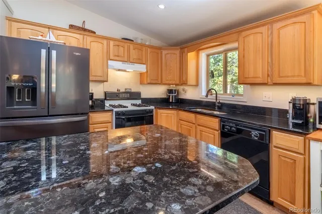 a kitchen with granite countertop a stove sink and cabinets