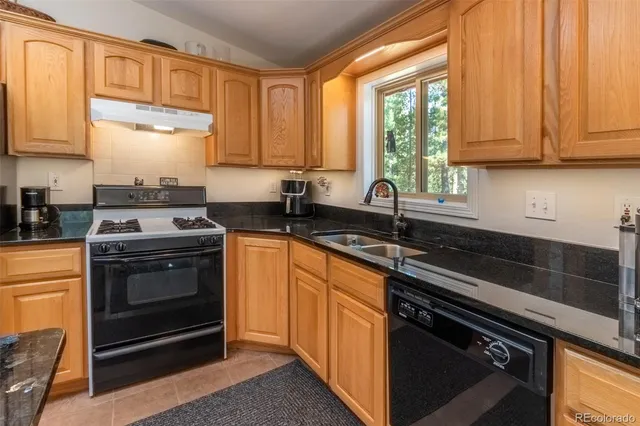 a kitchen with stainless steel appliances granite countertop a stove a refrigerator a sink a dining table and chairs with wooden floor