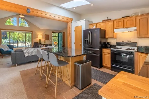 a kitchen with stainless steel appliances granite countertop a stove a refrigerator a sink a dining table and chairs with wooden floor