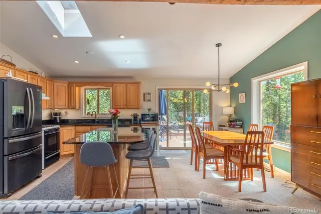 a kitchen with stainless steel appliances granite countertop a stove a refrigerator a kitchen island a stove and a dining table