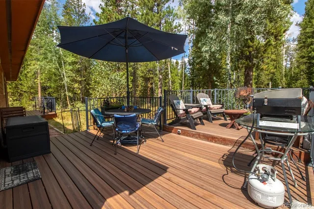 a view of a roof deck with table and chairs under an umbrella with wooden floor
