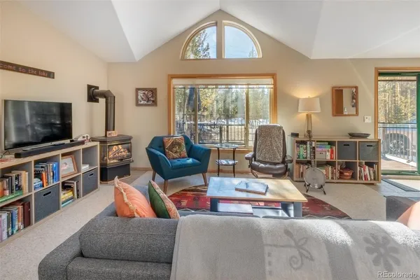 a living room with furniture a flat screen tv and floor to ceiling window
