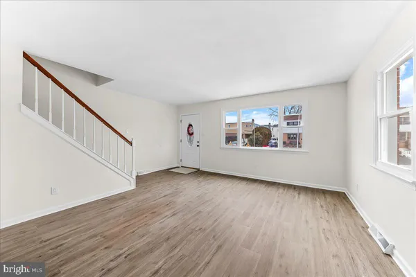 an empty room with wooden floor chandelier fan and windows