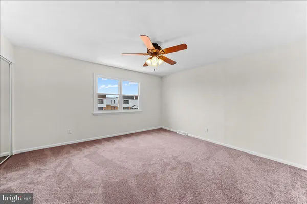 an empty room with closet and ceiling fan