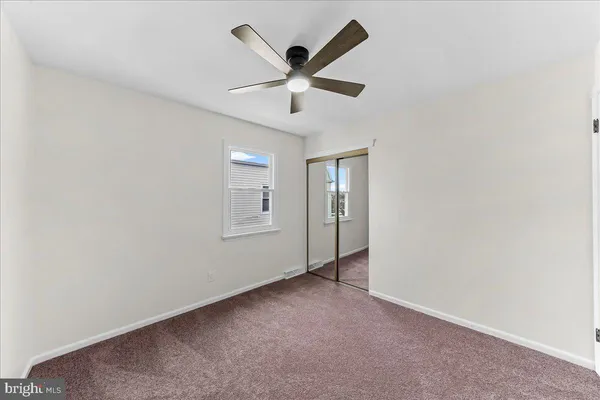 an empty room with ceiling fan and window