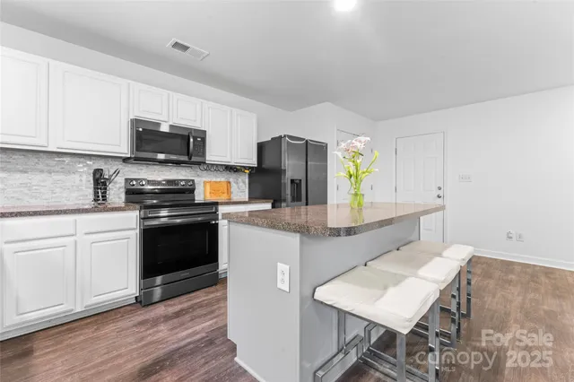 a kitchen with stainless steel appliances granite countertop a stove top oven a sink a counter space and cabinets