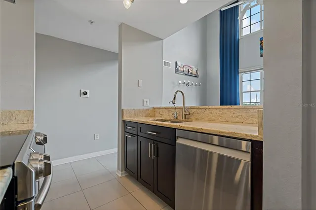 a kitchen with stainless steel appliances a refrigerator a sink dishwasher a dining table and chairs with wooden floor