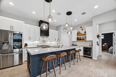 a kitchen with stainless steel appliances kitchen island granite countertop a stove a sink a oven a dining table and chairs