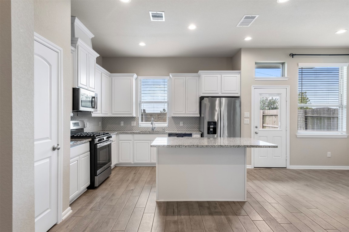 5203 Prairie Terrace Lane Fulshear, TX 77441 - Photo 7 of 32 a open kitchen with stainless steel appliances granite countertop a stove top oven a refrigerator a sink and dishwasher with wooden floor