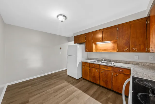a kitchen with stainless steel appliances granite countertop a sink and a stove top oven with wooden floor