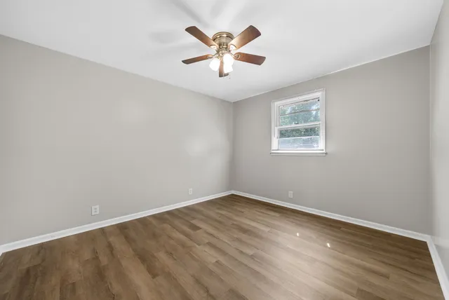 an empty room with wooden floor and ceiling fan
