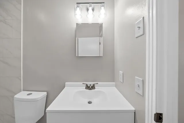 a bathroom with a sink and mirror with toilet