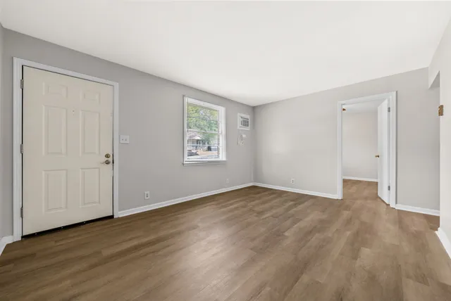 a view of an empty room with wooden floor and a window