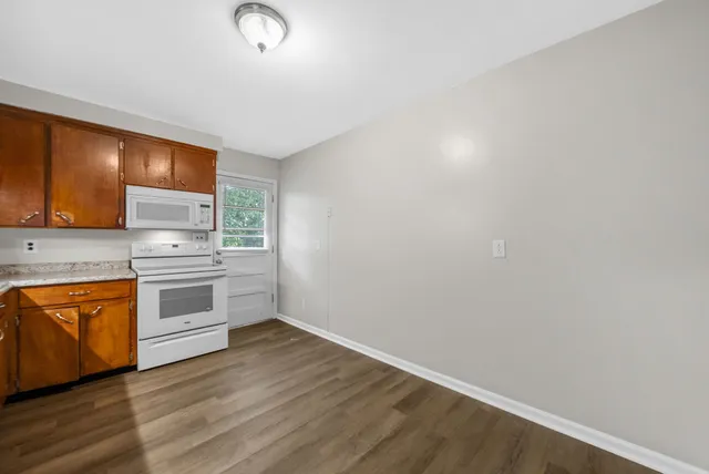 a kitchen with granite countertop a stove cabinets and wooden floor