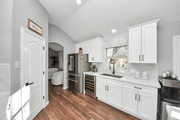 a kitchen with a sink dishwasher stove and white cabinets with wooden floor