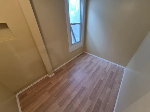 a view of empty room with window and wooden floor