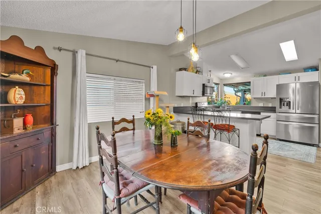a kitchen with stainless steel appliances kitchen island granite countertop a dining table chairs and a refrigerator