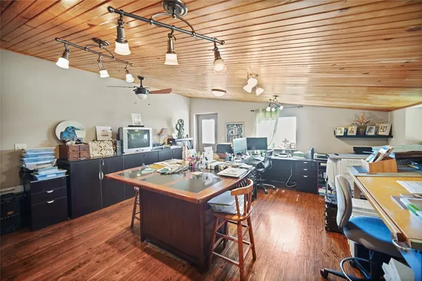 a room with stainless steel appliances kitchen island granite countertop a table chairs and a wooden floor