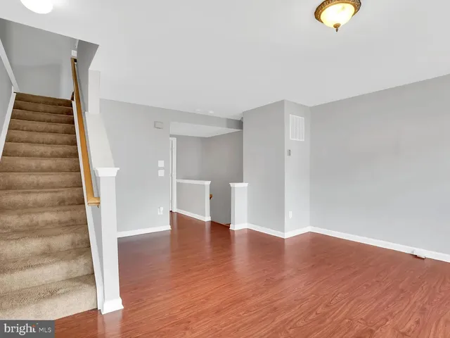 a view of an empty room with wooden floor and windows