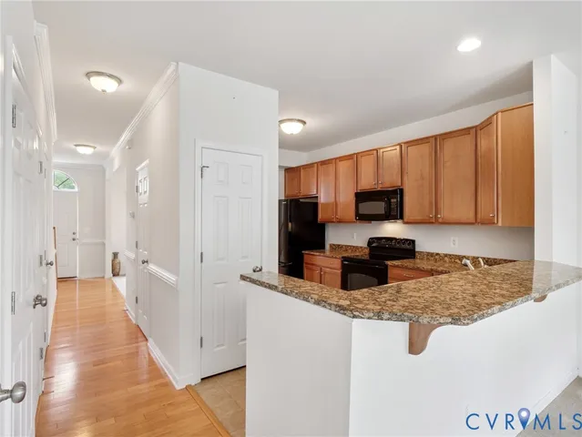 a kitchen with stainless steel appliances granite countertop a refrigerator a sink dishwasher a stove and white countertops with wooden floor